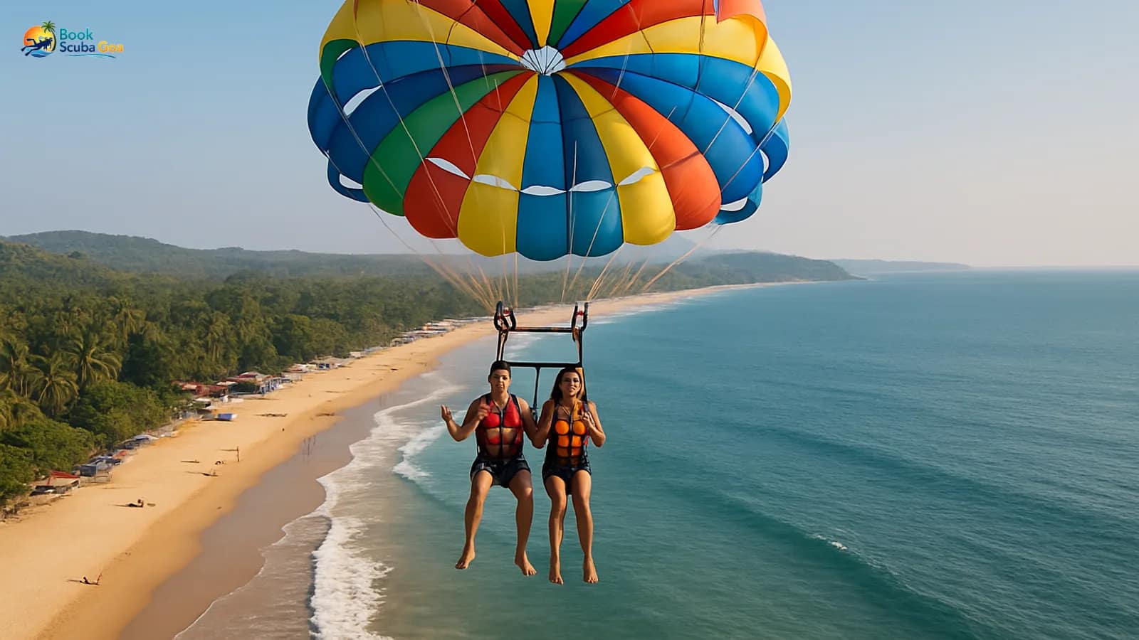 Parasail canopy lifting riders above a Goa beach